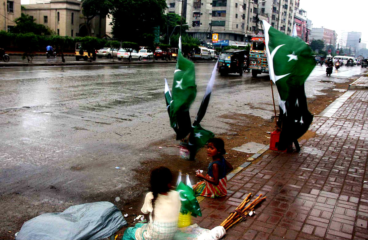 Girls Sitting At Roadside As The Sell National Flags To Earn Livelihood