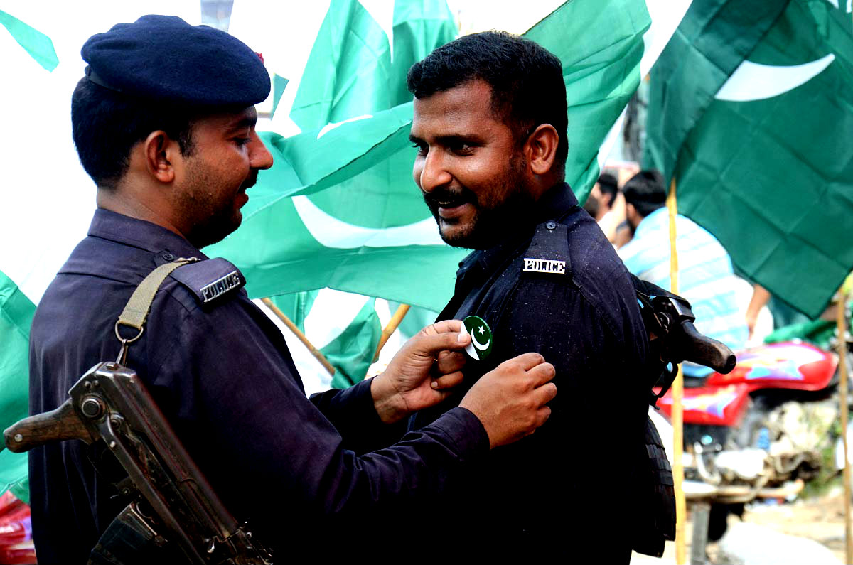 A Police Man Pinning A Badge Of Independence Day To His Colleague