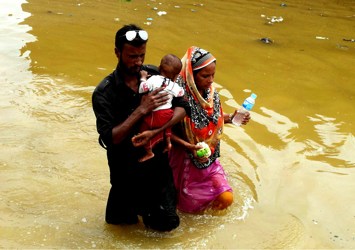 Man And A Woman With Child Seen Walk Flood Water After Heavy Monsoon