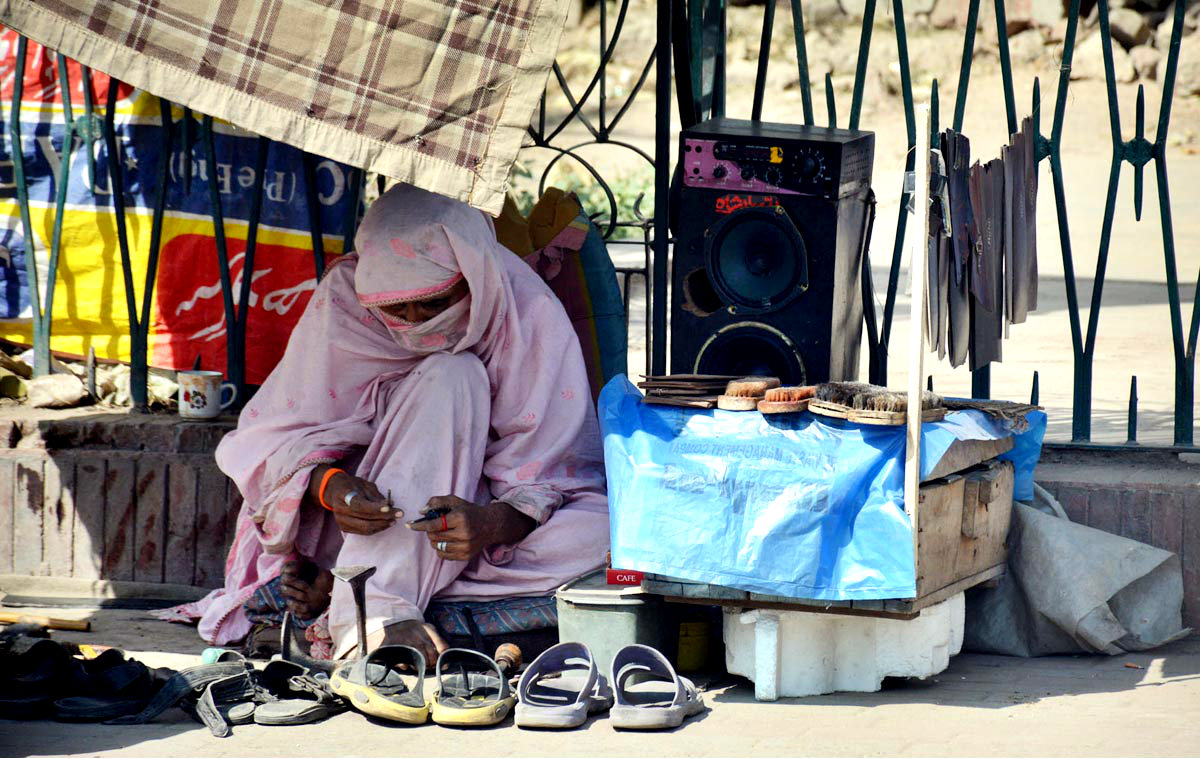 A Woman Seen Mending Shoes To Earn Livelihood