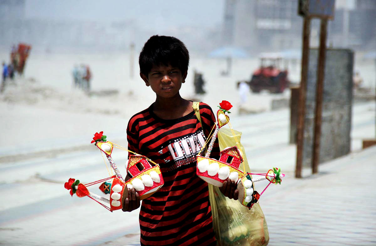 A boy Seen Selling Small Decoration Ships Near A Beach
