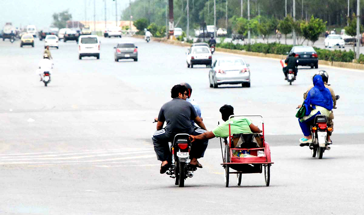 A Disabled Man Holding A Motorcycle While Travelling On Islamabad Highway