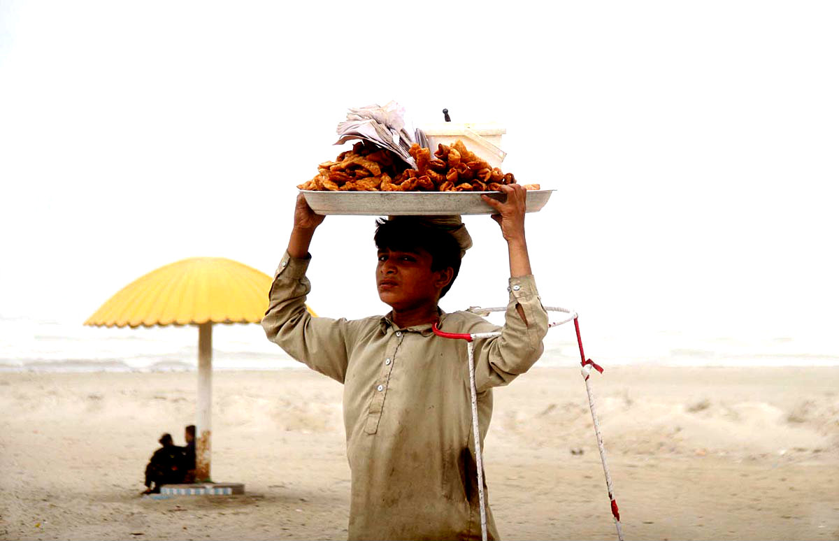 Karachi:A  Vendor Seen Carrying His Food Items For Selling At A Beach