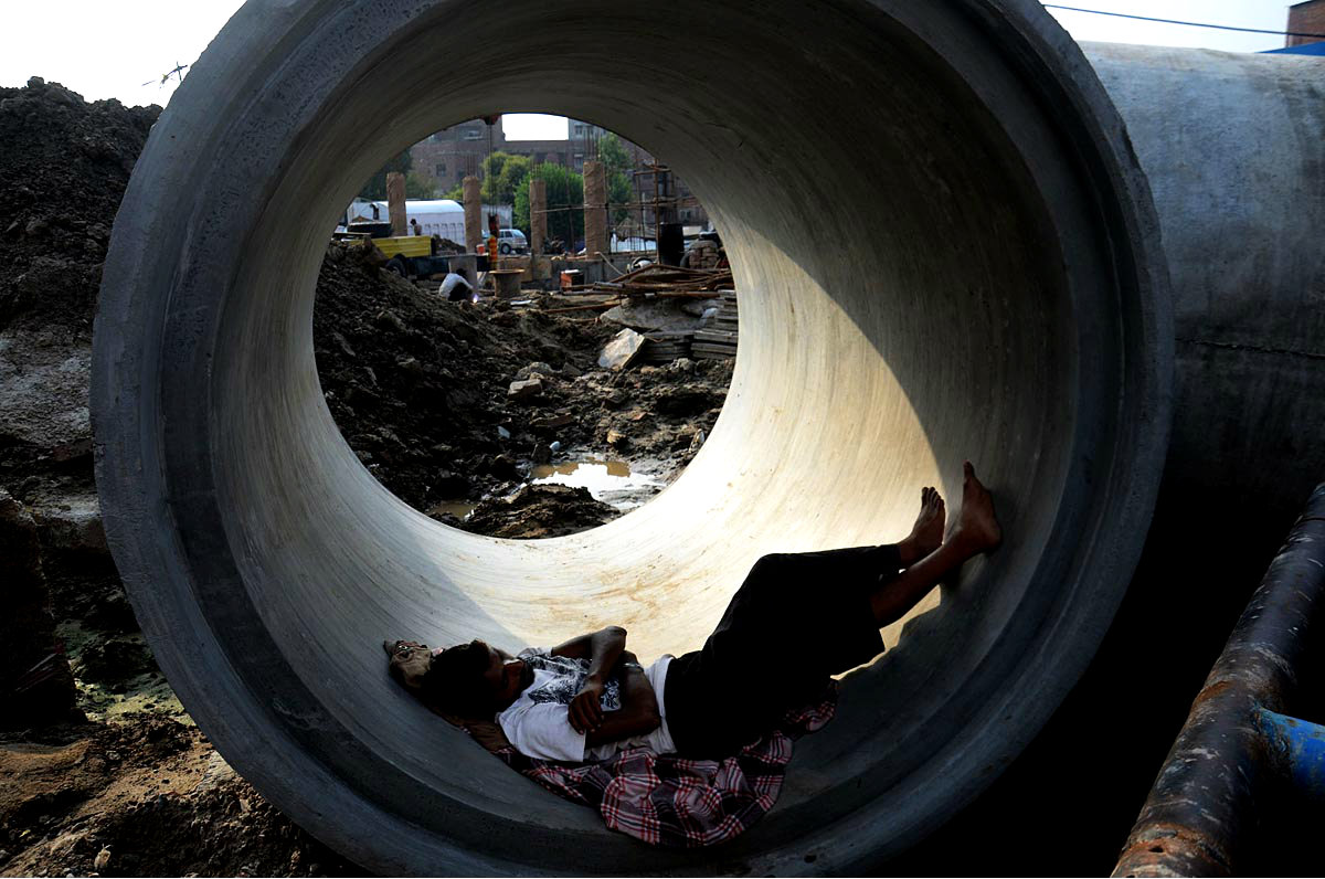 A Laborer Taking Rest At A sewerage Pipe