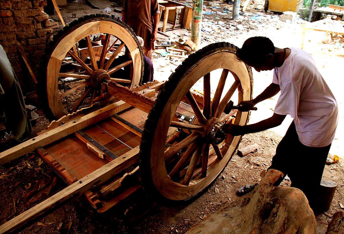 A Craftman Giving Final Touches To A Wooden Cart